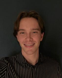 A picture of Pepijn. A man in front of a dark grey background, smiling with brown hair