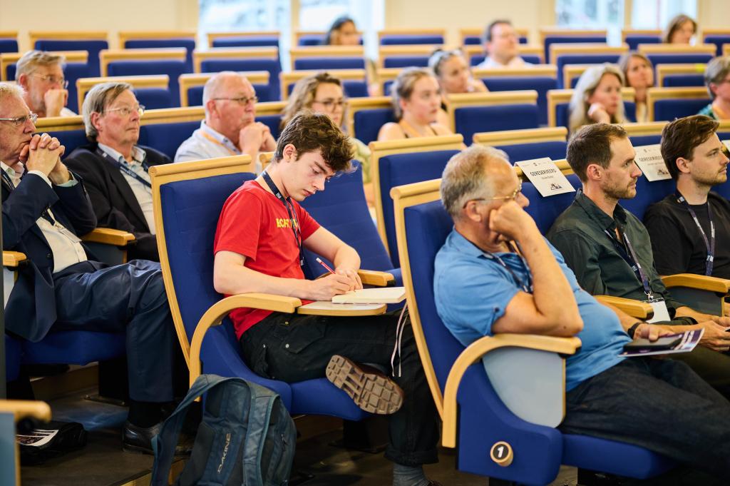 Interested people in audience, one of them is writing in his notebook