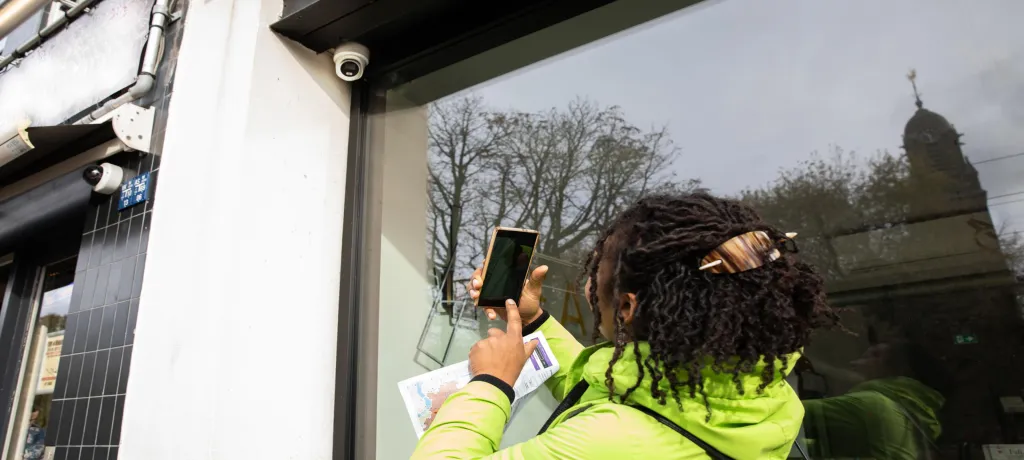 Woman taking a picture of a surveillance camera in the city