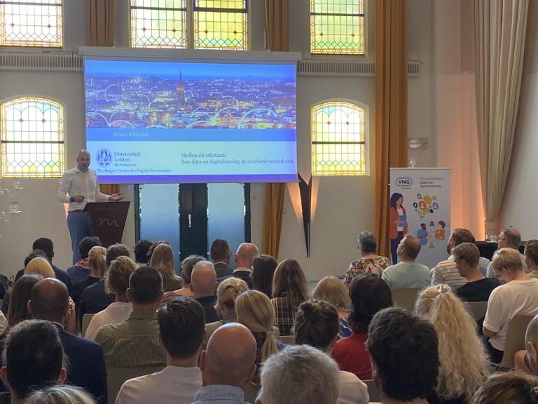 Bram Klievink left holds a speech in front of a fully packed room
