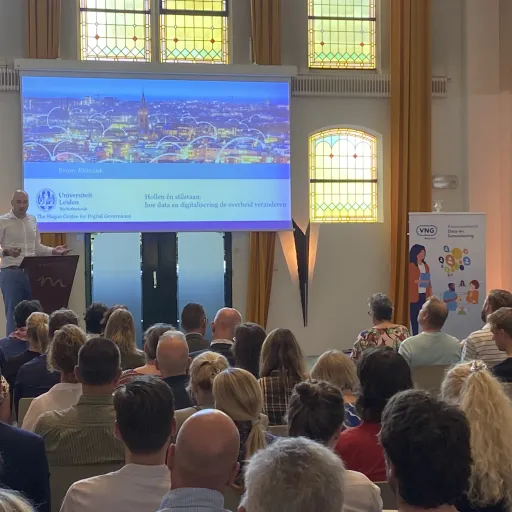 Bram Klievink left holds a speech in front of a fully packed room