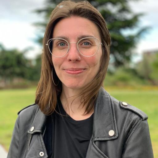 Isa Sanchez Cecilia. A picture of a young women wearing a leather jacket. She has brown hair, glasses and a nose piercing and is standing in nature. 