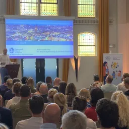 Bram Klievink left holds a speech in front of a fully packed room